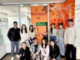 Six men and women stand front of a glass wall decorated with A Nightmare on Cell St.