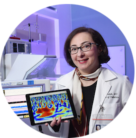 Dr. Chalak holding a tablet and smiling for the camera in the lab