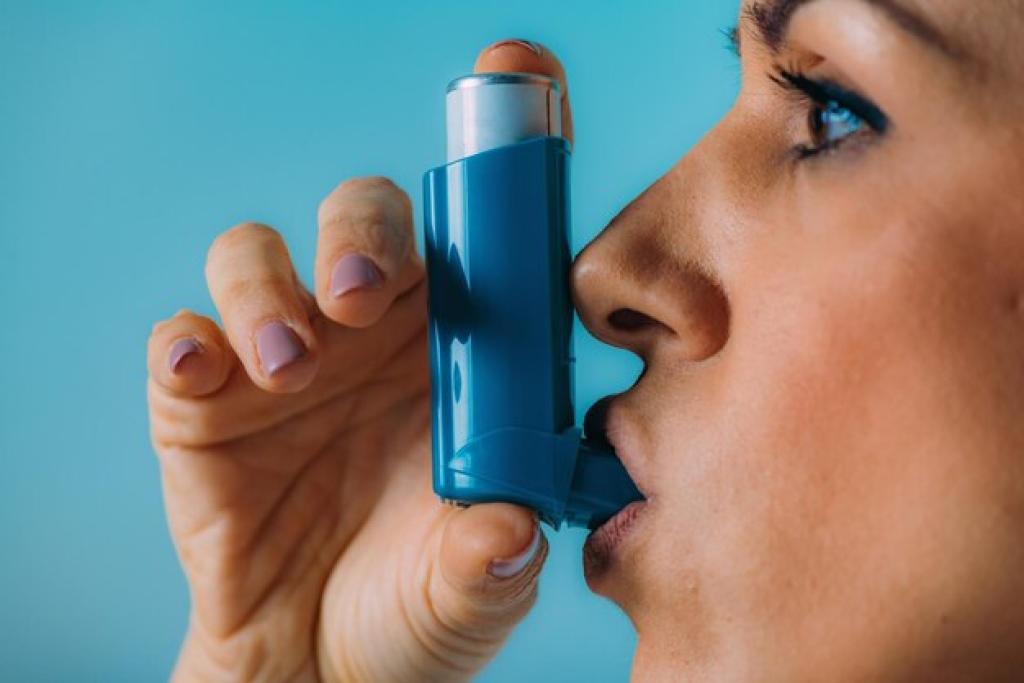 Woman using asthma inhaler