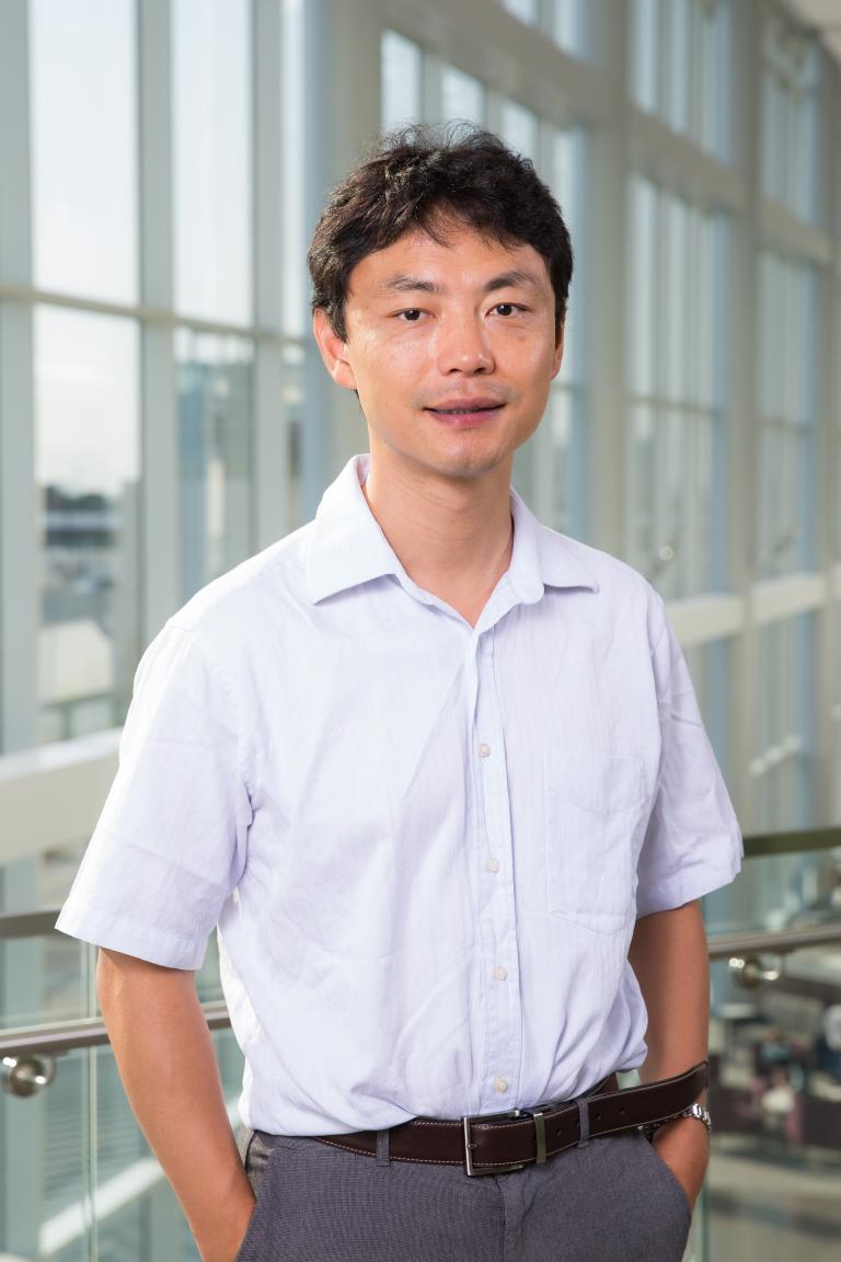 Smiling man with dark brown hair, wearing a white shirt.