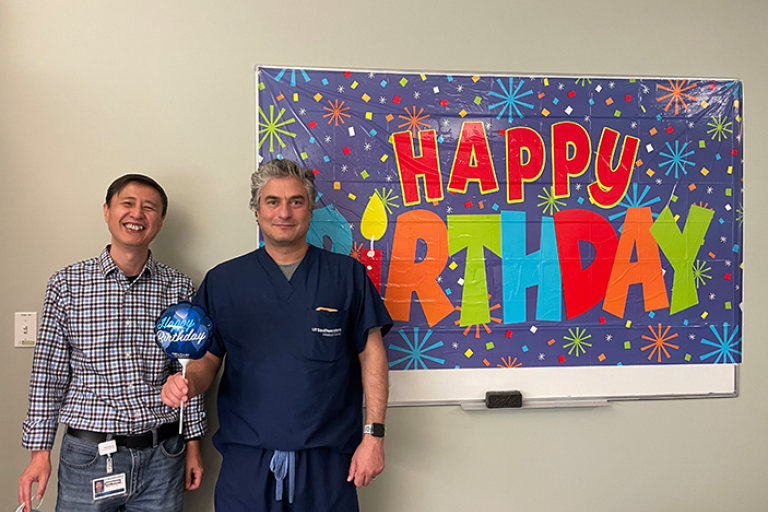 Dr. Sumer and Gang standing in front of "Happy Birthday" banner