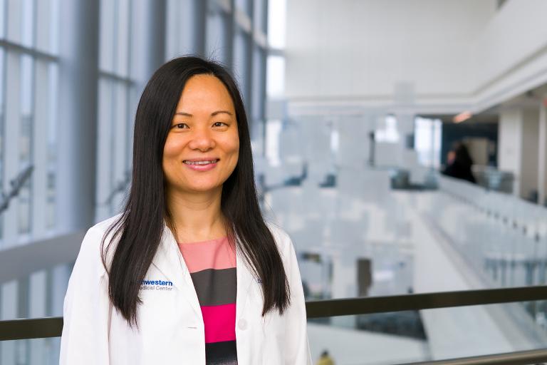 Dr. Dan (Amanda) Tong in a white coat standing in a hospital lobby