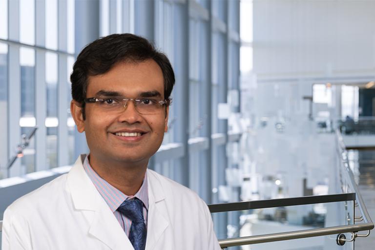 Dr. Ambarish Pandey in a white lab coat standing in hospital lobby