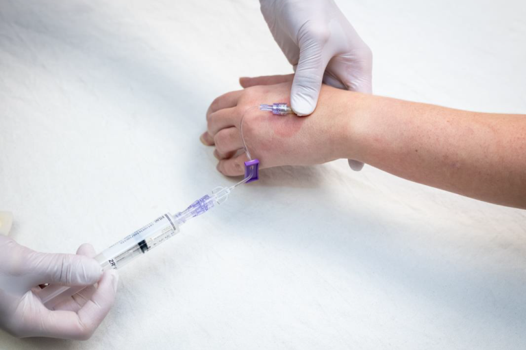 patient arm being prepped for an IV as a tube in inserted into vein