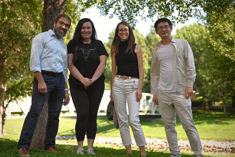 members of the Suleiman Lab standing in a line outdoors among trees