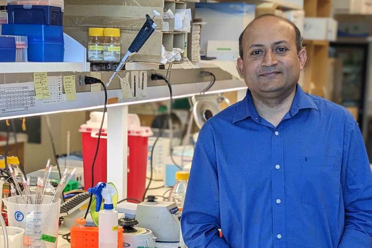 \Smiling man with short hair and blue shirt stands in a lab.