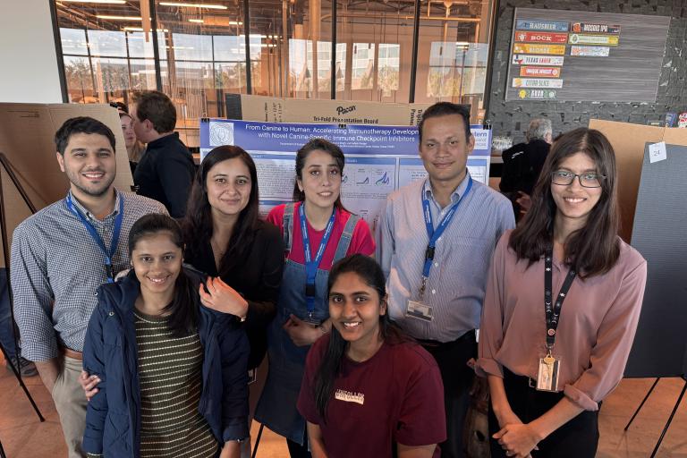 A group of seven people posing for a photo in front of a display board.