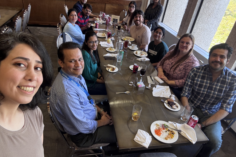 A group of people sitting at a long table with food on it.