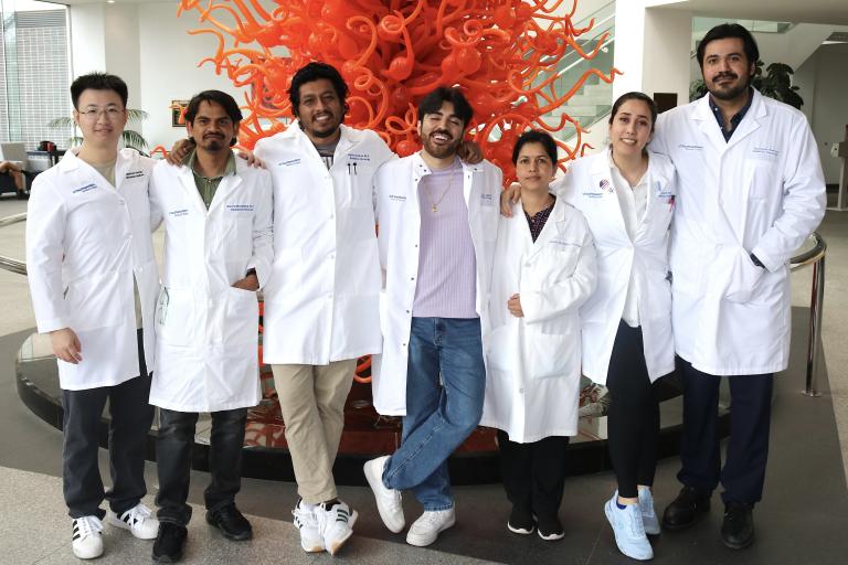 Ranjan Lab team standing in front of an orange sculpture.