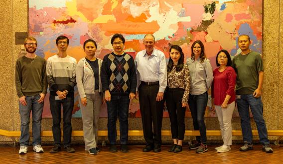 9 team members posed in front of an abstract art exhibit.