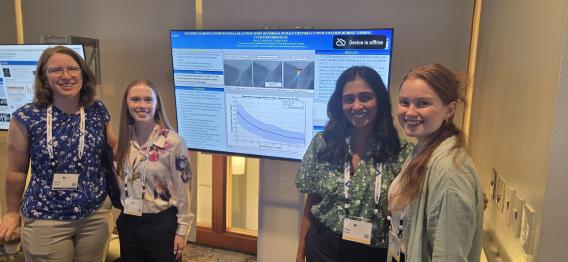 Zoe Bass, Christie, Gandra and Zone standing near their poster in the middle