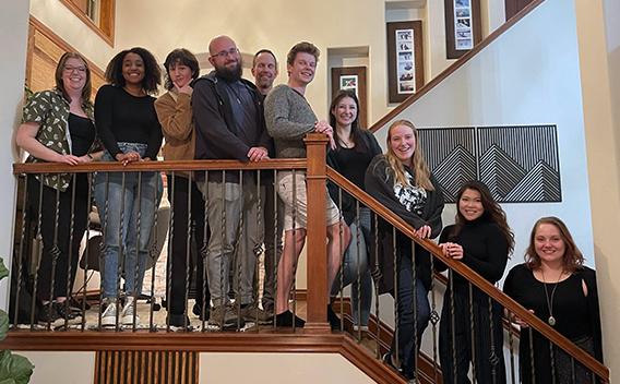 Lab Members of the Beckham lab in a house standing on a staircase.