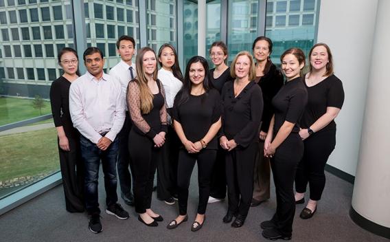 Members of the Conzen Research Lab group all wearing black and white standing in front of a large window