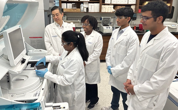 a group of people in a lab around a computer monitor