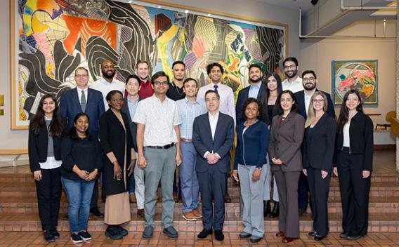 The Cardiometabolic Research Unit group standing on a brick floor in front of an abstract painting 