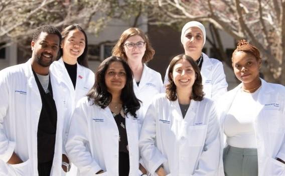 group of 7 medical researchers in a group outdoors all wearing white coats