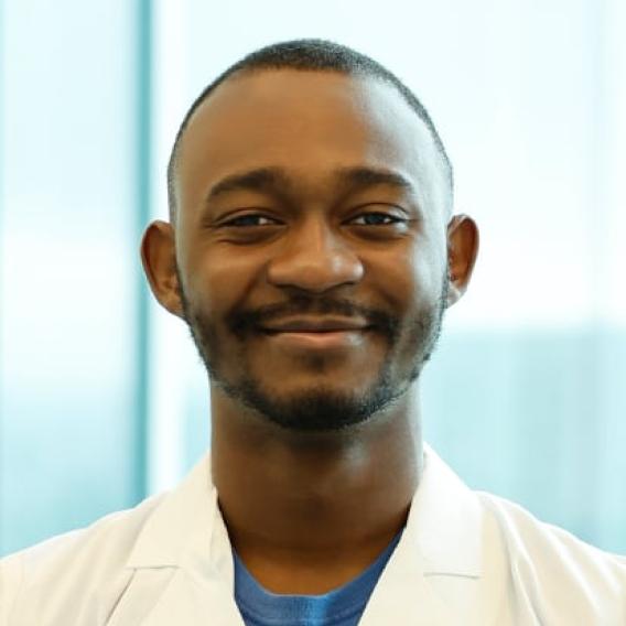 Oreoluwa Onabolu with dark hair and beard wearing a lab coat.