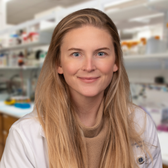 Marguerite Monogue  in a white coat standing in a labotratory