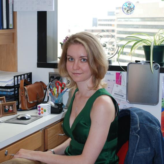 Dr. Davis, with medium-length blond hair wearing a green summer dress, sitting in an office.