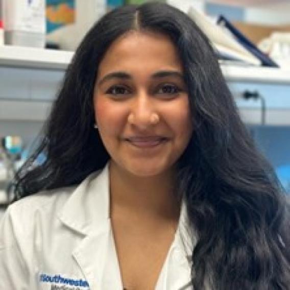 Smiling woman with long dark hair, wearing a lab coat.