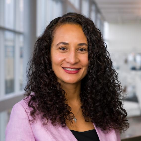 Smiling woman with long dark curly hair.