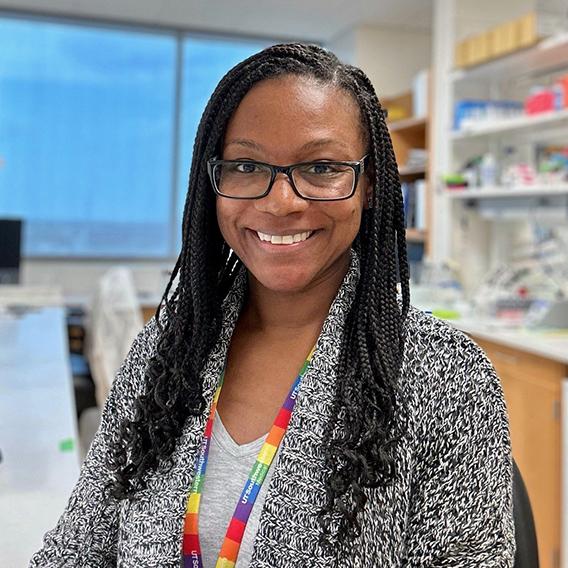 Crystal King, smiling woman with long dark hair, sitting in a lab.