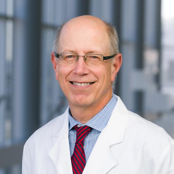 a man with glasses wearing a stipped tie and a white lab coat.