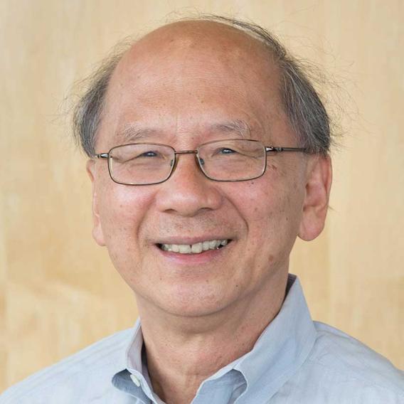 Smiling man, balding with gray hair, wearing a blue shirt and wire rimmed glasses.