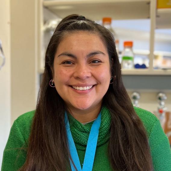 Claudia Munoz Rodriguez wearing a green shirt standing in a laboratory