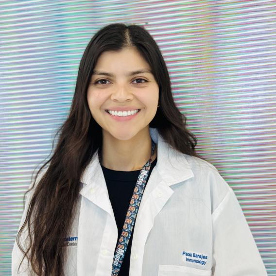Photo of girl smiling in front of art work wearing a lab coat