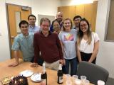 Lab group gathered for David's birthday, with cake, plates, cups and champaign