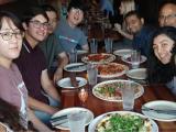 Nine lab members sit around table with food