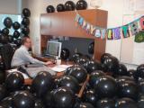 PI working in office filled with balloons, with birthday banner on the wall