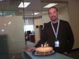 Team member with cake, about to blow out 3 candles