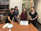 Julio, Aparna, Anna and Anne gather with cake and half empty bottle of whiskey and a bottle of champagne