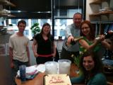 Five team members in office, celebrating with champaign and cake