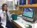 Team member in lab working, while watching soccer on computer screen