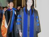 Two students walking at graduation, wearing robes