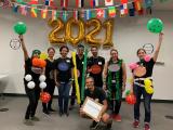 D'orso Lab team in 2021 celebrating lab olympics with balloons. Dr. D'Orso kneels in front holding a sign that says "Transcription"