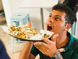 a man pouring tacos in his mouth from a plate