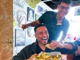a man with a plate of tacos, laughing