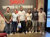 the lab group standing in front of a wall that says smile because it happened