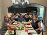 five people sitting around a dinner table 