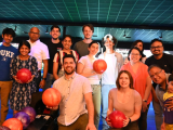 Large group of people pose for camera in front of bowling alley lanes