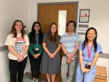 Dr. Dan Tong with four lab members gathered in front of the laboratory doorway