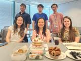 members of the Dan Tong lab sitting and standing in front of a table of food