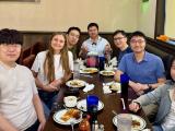 A group of people posed around a restaurant table with food and drink.