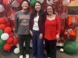 Three people gathered in front of Christmas Decorations.