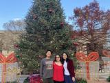 Three people gathered in front of a Christmas tree.
