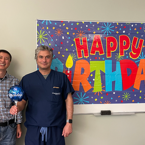 Dr. Sumer and Gang standing in front of "Happy Birthday" banner
